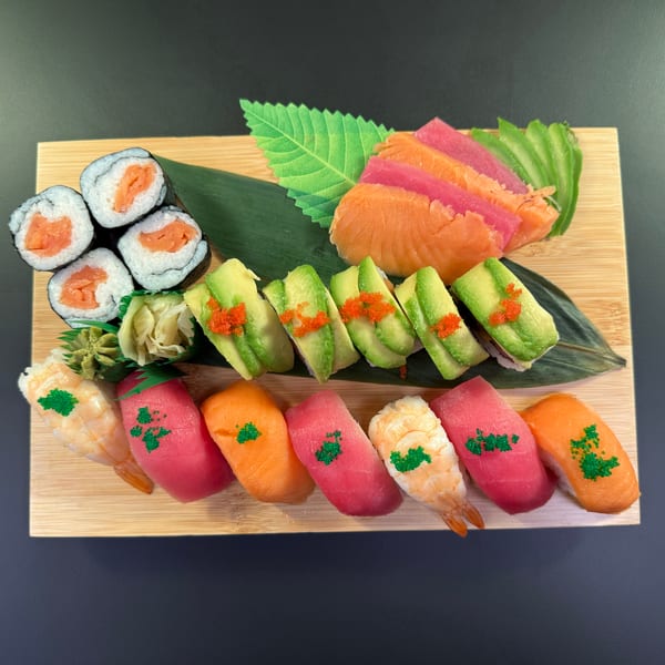Assorted sushi platter with salmon rolls, avocado rolls, nigiri, and sashimi on a wooden board.