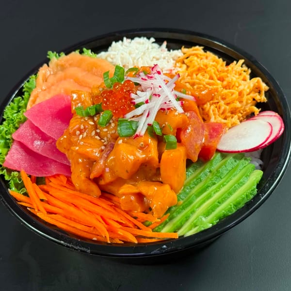 Colorful poke bowl with salmon, tuna, avocado, carrots, and rice on a dark background.