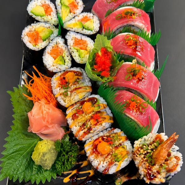 A black platter filled with various colorful sushi rolls, including tuna, salmon, and shrimp.